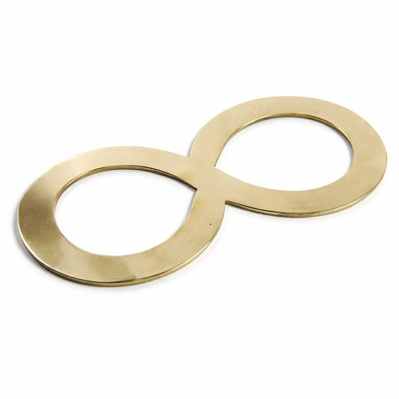 Flaches Metallobjekt in liegender Achtform aus goldfarbenem Material vor hellem Hintergrund